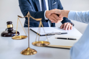 A personal injury lawyer shakes hands with a client across a desk, symbolizing agreement and trust in legal representation.